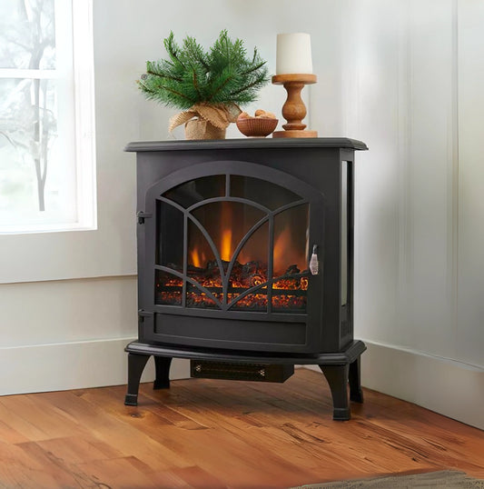 Black electric stove with glowing interior, decorative items on top, in a room with wooden floor and window.